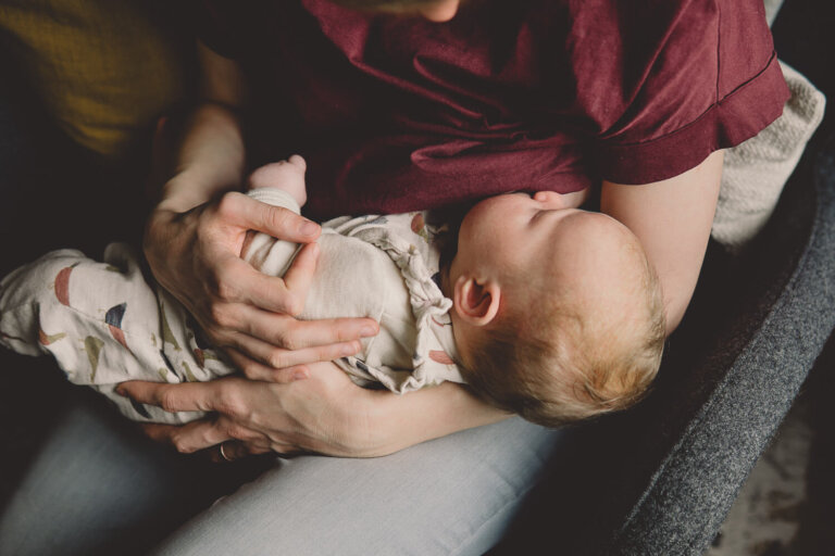 Nahaufnahme von einer stillenden Mama die liebevoll ihr Baby im Arm hält fotografiert von Dorothee Moser Familienfotografin in Würzburg und Umgebung.